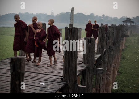 Un groupe de moines bouddhistes débutants marche sur le pont U Bein, Amarapura, Myanmar. Banque D'Images