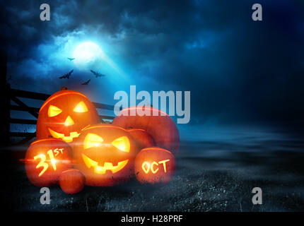 Un groupe de Jack O Lantern halloween pumpkins avec des visages souriants brillants dans le soir de lune. Banque D'Images