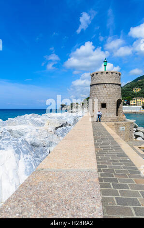 Un homme âgé sur sea wall reading newspaper Recco Italie Banque D'Images