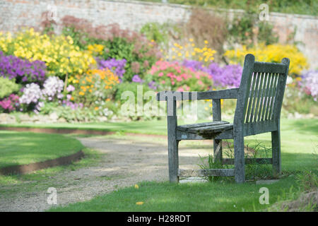 Jardin vide siège en face de la frontière herbacées colorées à l'automne à Waterperry gardens, Oxfordshire, Angleterre Banque D'Images