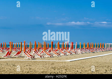 Orange vide chaises longues et parasols sur la plage, au début de saison, Viareggio, Toscane, Italie Banque D'Images