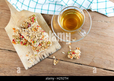 Barre granola céréales croustillantes ou des biscuits de riz avec un verre tasse de thé chaud sur la table de bois. Banque D'Images