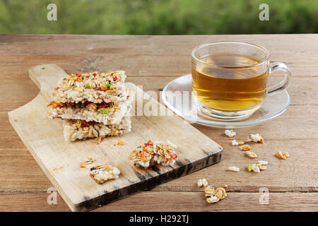 Barre granola céréales croustillantes ou des biscuits de riz avec un verre tasse de thé chaud sur la table de bois. Banque D'Images