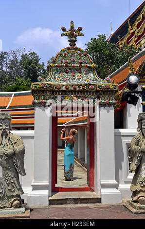 Un tourisme de l'Ouest prend des photos à temple de Wat Pho à Bangkok, Thaïlande, encadré par une porte, avec statue gardes. Banque D'Images