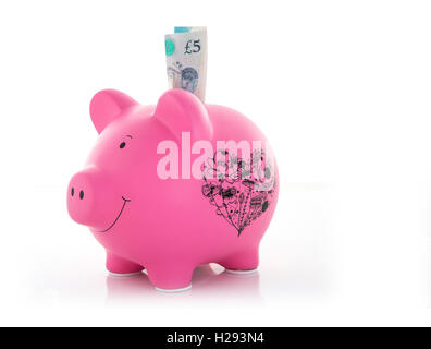 Pink Piggy Bank avec cinq nouveaux pound note sur un fond blanc Banque D'Images