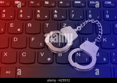 La cybercriminalité concept avec petites menottes sur clavier d'ordinateur Banque D'Images