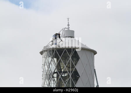 Harnais de sécurité et cordes tout en travaillant en hauteur dans un environnement inhabituel, peintre peignant le sommet du phare à St John's point Co Down. Banque D'Images