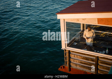 Waiter prépare tables du restaurant sur le quai juste au-dessus des vagues de l'océan Atlantique, Swakopmund, Namibie Banque D'Images