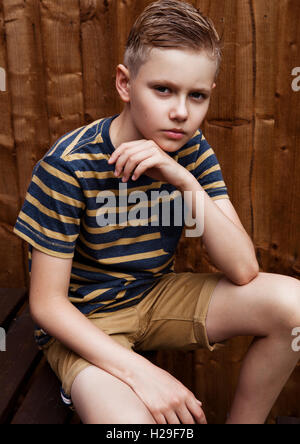 Portrait of handsome young happy boy piscine dans jardin.Brown wood background Banque D'Images