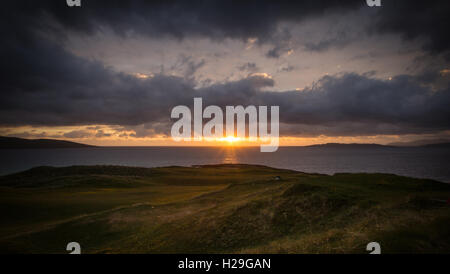 Le soleil se couche sur l'horizon de l'Océan Atlantique derrière Scarista de Golf sur la côte ouest de l'île de Harris, Hébrides extérieures, en Écosse. Banque D'Images