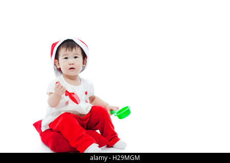 Petite fille de Noël assis sur l'oreiller et l'attente à santa hat ,isolé sur fond blanc Banque D'Images