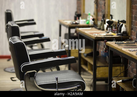 Rangée de fauteuils en cuir noir à l'intérieur salon de coiffure moderne. L'intérieur horizontal tourné Banque D'Images