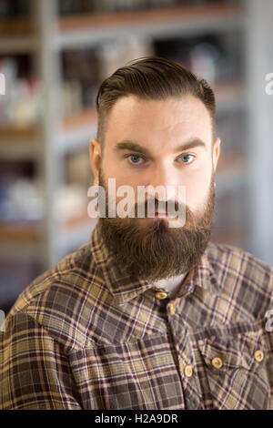 Portrait Portrait de jeune homme sérieux avec longue barbe et moustache. Beau barbu posant avec les mains croisées sur sa poitrine Banque D'Images