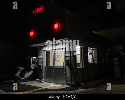 Nuit rue au Japon, un policier en service dans un Koban, scooter de police garée à l'extérieur. La gare la nisshin, Saitama, Japon Banque D'Images