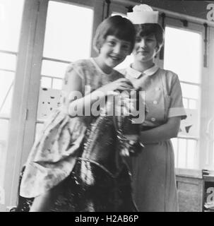 Infirmière avec un enfant sur le cheval à bascule. Les infirmières à un hôpital d'enseignement de l'habitation à Leicester c1962. Photo par Tony Henshaw Banque D'Images