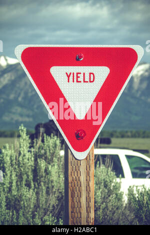 Grand signe de rendement rouge dans un coin de campagne avec des montagnes Banque D'Images