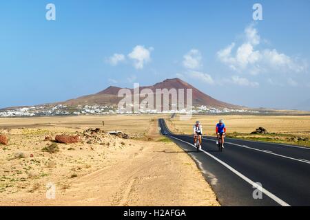 Le vélo sur la LZ-401 route de cône volcanique s'élevant au-dessus de village de Soo. Teguise, Lanzarote, îles Canaries, Espagne Banque D'Images