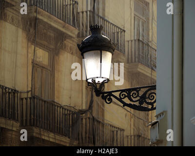 Soleil blanc sur plaque de verre et le support aux éléments en fer forgé se détachant sur la façade de l'immeuble aux balustrades en pierre dans l'ombre tamisée Espagne Banque D'Images