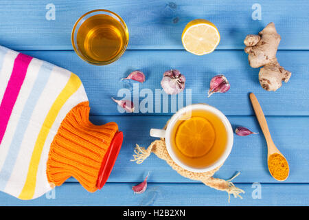 Bouteille d'eau chaude, une tasse de thé chaud avec du citron et ingrédients pour la préparation de boissons réchauffement Grippe et rhume, Banque D'Images