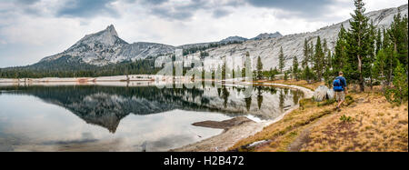 Jeune homme sur le sentier de randonnée au lac, les montagnes reflétée dans un lac, Cathedral Peak, Lac de la cathédrale, la Sierra Nevada Banque D'Images