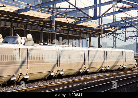 Le Japon. Fukuyama. Afficher le long de la n700 series, Shinkansen bullet train en gare, coucher de soleil très fort le blanchiment de la couleur du train. Banque D'Images