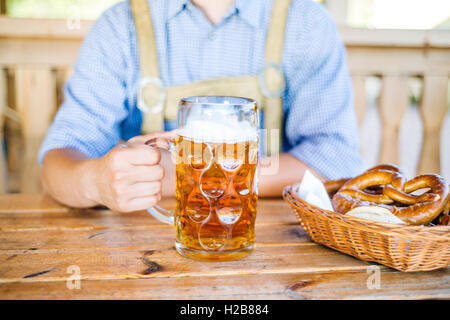 L'homme en habits traditionnels bavarois avec de la bière et des bretzels Banque D'Images