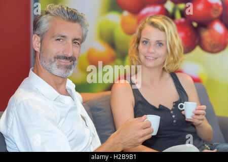 Couple assis sur table holding cup de verre Banque D'Images