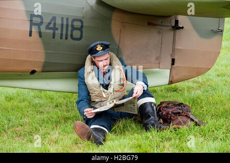 Re-Enactor vêtue comme une bataille d'Angleterre 'pilote attend une bousculade' avec son Hawker Hurricane fighter Banque D'Images