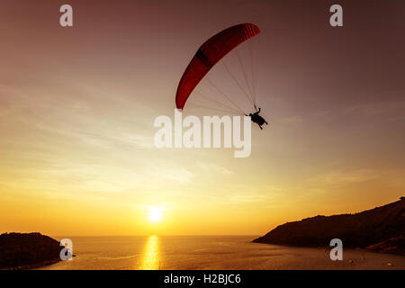 Silhouette de parachutiste vole sur fond de ciel de coucher du soleil et mer Banque D'Images