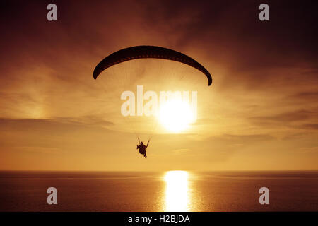 Silhouette de parachutiste sur le coucher du soleil et l'arrière-plan de la mer Banque D'Images