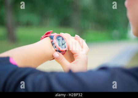 Jeune fille fitness chronomètre chèques tracker sur son poignet, durant la course outdoor Banque D'Images