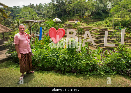 L'INDONÉSIE, Bali, Tegallang, wearing sarong à J'aime (coeur) sign in Bali garden cafe Banque D'Images