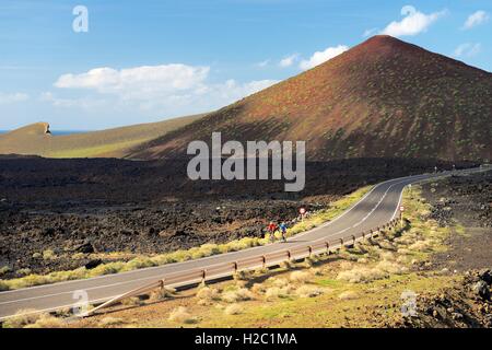 Les cyclistes traversent sur le paysage de lave LZ-704 route venant de El Golfo. Le Parc National de Timanfaya, Lanzarote, îles Canaries, Espagne Banque D'Images