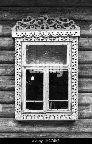 Détails de l'architecture russe rurale traditionnelle. Fenêtre avec cadre en bois sculpté dans le mur fait de bois rugueux, noir et blanc retr Banque D'Images