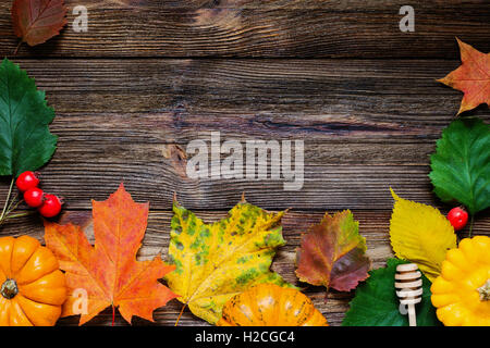 Tombée feuilles d'érable et les petites citrouilles sur fond de bois. Carte d'automne Banque D'Images