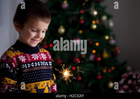 Beau petit enfant tenant burning sparkler le soir du Nouvel An, des vêtements décontractés, feu de Bengale Banque D'Images