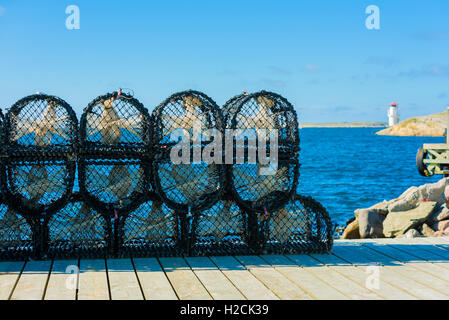 Pile de cages de homard ou des pots sur la jetée avec la ville suédoise d'Mollesund phare en arrière-plan. Banque D'Images