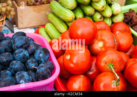 Tomates rouges, prunes bleu marine, vert les concombres, les raisins et abricots secs à l'écran en vente sur une foire locale. Banque D'Images