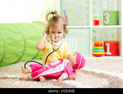 Kid Girl Playing Doctor avec une poupée dans les jeux pour enfants Banque D'Images