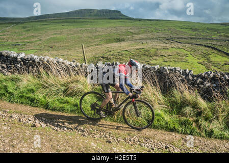 Un cavalier en ordre décroissant Penyghent dans les 3 pics 2016 cyclocross, Yorkshire Dales, au Royaume-Uni. Banque D'Images