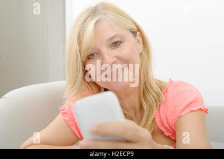 Smiling senior woman using smartphone à la maison Banque D'Images