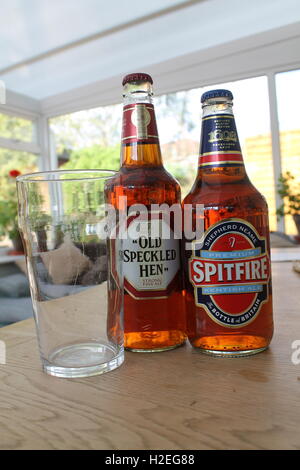 Old Speckled Hen et Spitfire les bouteilles de bière avec un verre de bière sur une table de jardin Banque D'Images