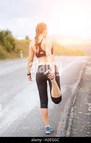 Jeune femme fitness runner stretching jambes avant de courir dans les montagnes Banque D'Images