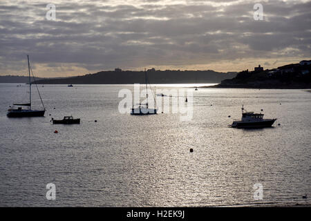 St Mawes Harbour au coucher du soleil avec les bateaux de pêche et yachts, plus St Mawes Château et le château de Pendennis, Falmouth, en silhouette Banque D'Images