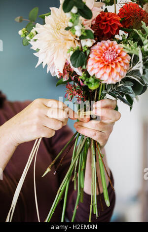 Des arrangements de fleurs biologiques. Une femme de la création d'un bouquet attachés à la main. Banque D'Images