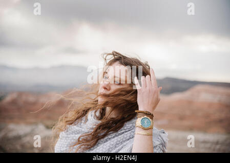 Une femme avec lon g les cheveux au vent debout dans un paysage désertique. Banque D'Images