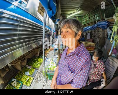 Samut Songkhram, Samut Songkhram, Thaïlande. 27 Sep, 2016. Une femme qui travaillent dans le marché des montres Samut Songkhram gare un train entre en gare. Le train de l'Baen Laem à Samut Songkhram (Mae Khlong) récemment repris du service. La piste de 33 kilomètres a été fermée pour réparation pendant près d'un an. Dans Samut Songkhram, le train passe sur le marché. Tirer sur leurs stands des fournisseurs à l'écart et les gens sortir de la façon que le train passe à travers le marché. C'est l'une des plus célèbres stations de train en Thaïlande et est devenu une importante attraction touristique dans la pers Banque D'Images