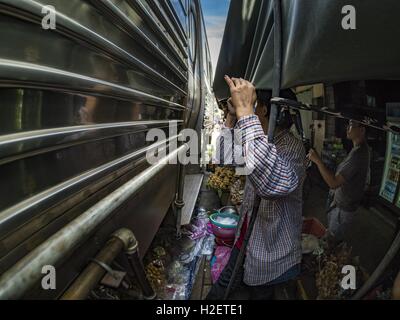 Samut Songkhram, Samut Songkhram, Thaïlande. 27 Sep, 2016. Une femme qui travaillent dans le marché des montres Samut Songkhram gare un train entre en gare. Le train de l'Baen Laem à Samut Songkhram (Mae Khlong) récemment repris du service. La piste de 33 kilomètres a été fermée pour réparation pendant près d'un an. Dans Samut Songkhram, le train passe sur le marché. Tirer sur leurs stands des fournisseurs à l'écart et les gens sortir de la façon que le train passe à travers le marché. C'est l'une des plus célèbres stations de train en Thaïlande et est devenu une importante attraction touristique dans la pers Banque D'Images