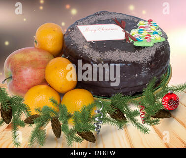 Sur la table en bois sont des cadeaux de Noël : délicieux gâteau au chocolat, mandarine, décorations pour arbres de Noël. Banque D'Images