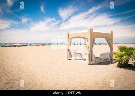 De couleur sable gazebo avec des chaises blanches sur la plage. Banque D'Images